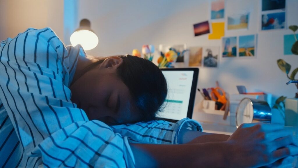 il bornout del digital creator: una ragazza dorme mentre lavora al computer.