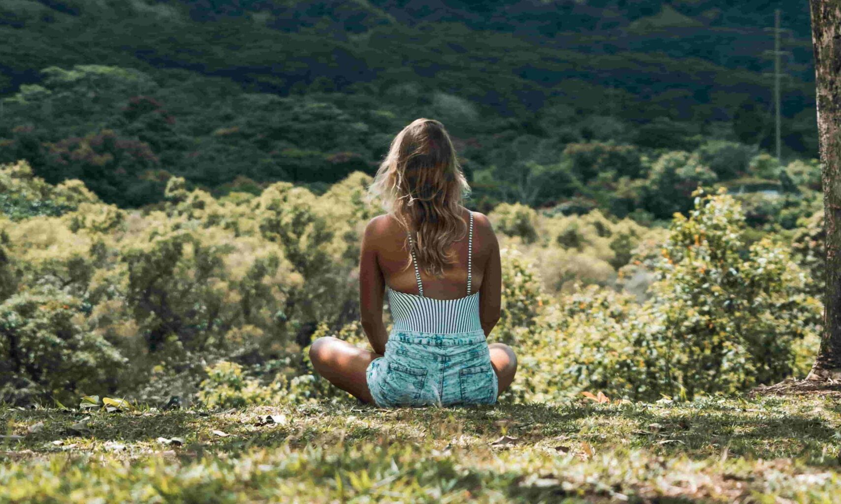 ragazza pratica la mindfulness seduta nel bosco