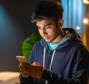 Un ragazzo con dipendenza da social guarda il suo smartphone